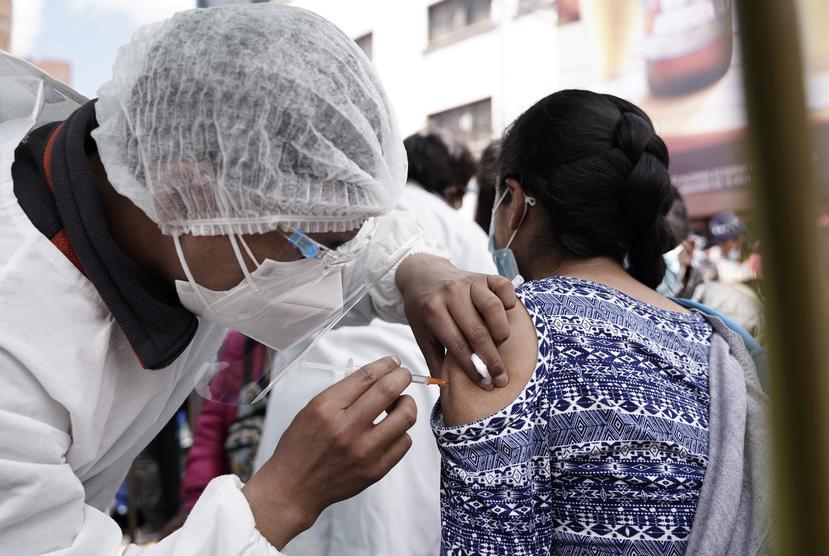 Un trabajador de salud aplica a una mujer la primera dosis de la vacuna Sinopharm fuera de la iglesia Monte de Oración en La Paz, Bolivia.